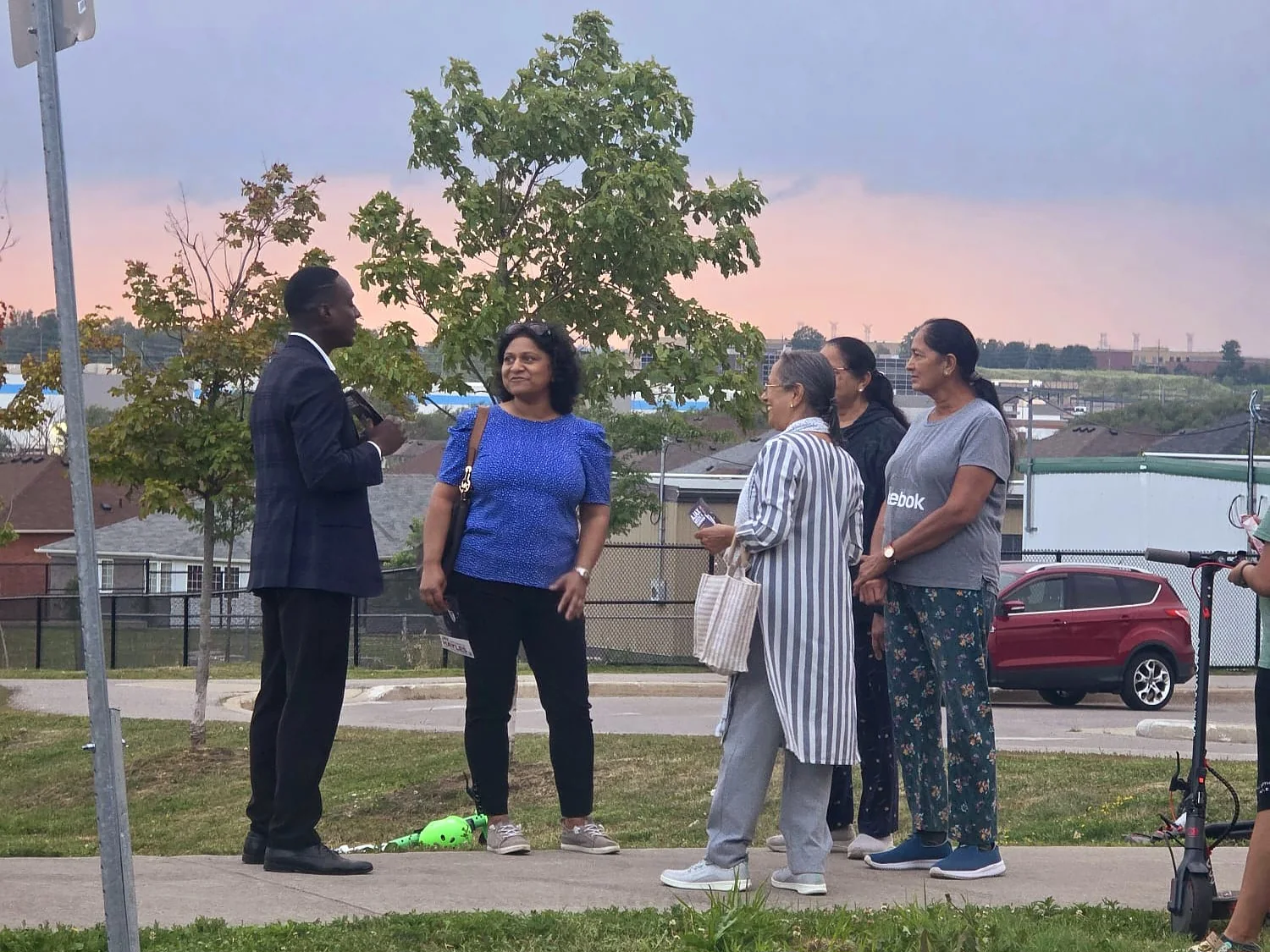 Jay Hayles talking with a group of residents on a Ward 2 street at dusk