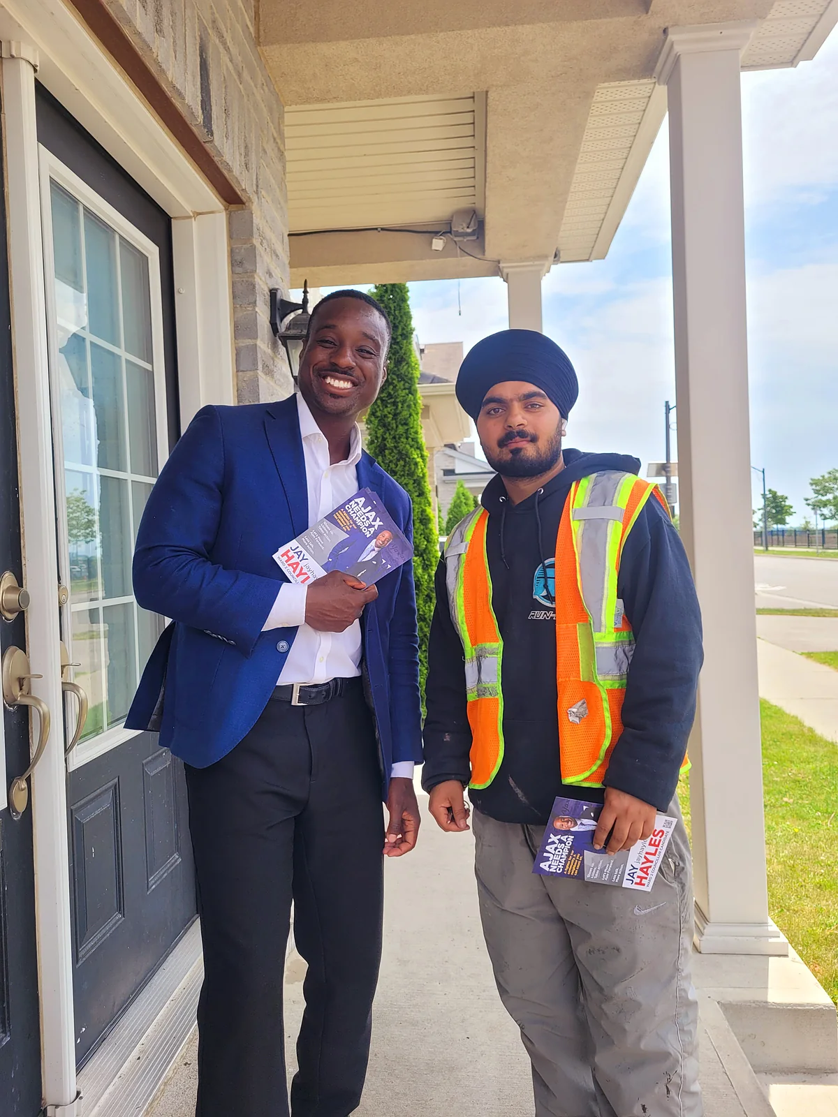 Jay Hayles on a front porch with a Ward 2 resident in a hi-vis work vest