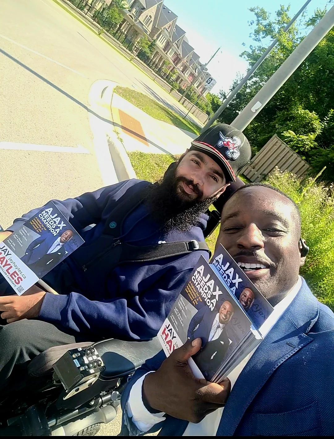Jay Hayles and a resident on a motorcycle, both holding campaign literature