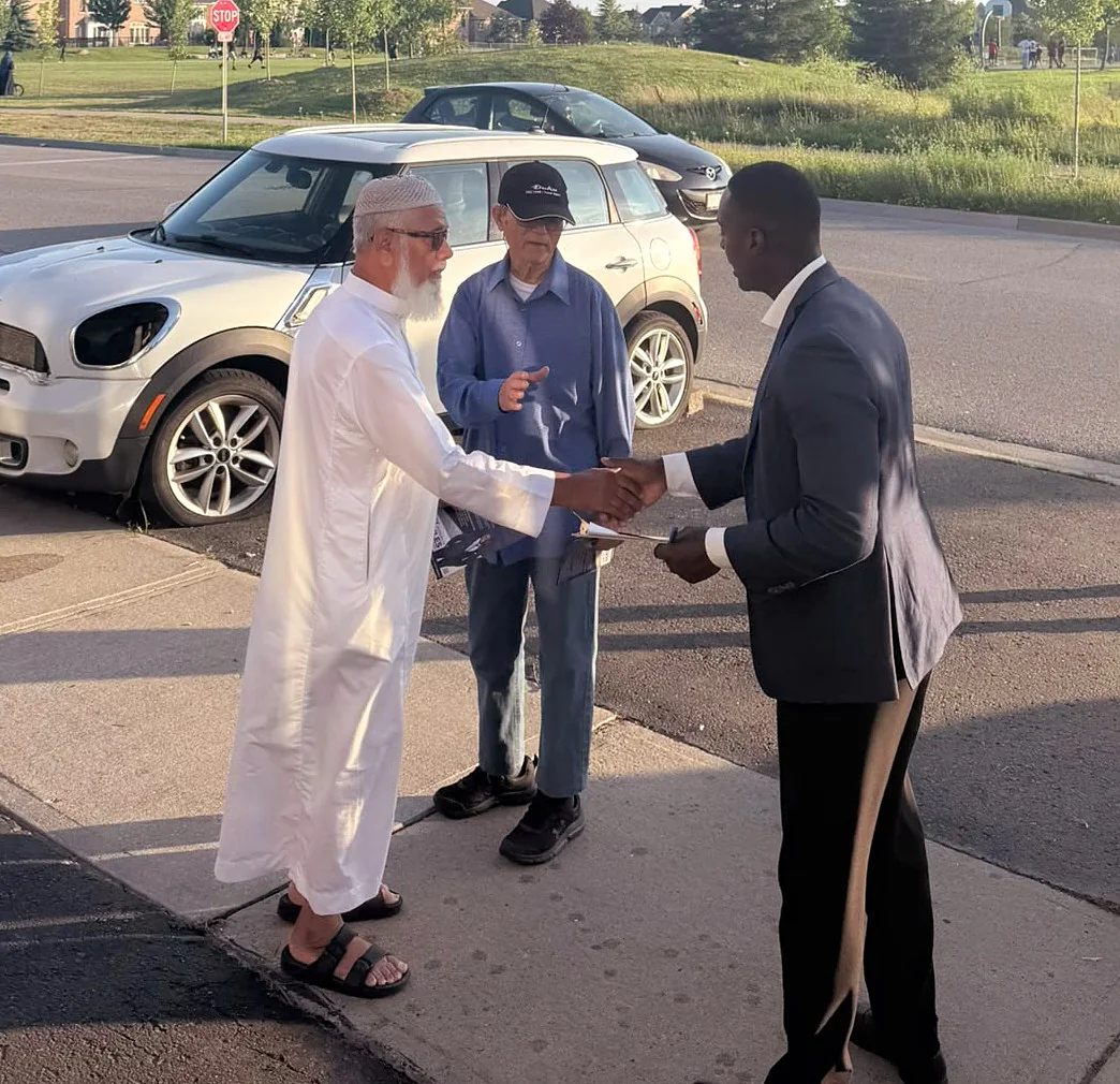 Jay Hayles shaking hands with two residents on a Ward 2 street